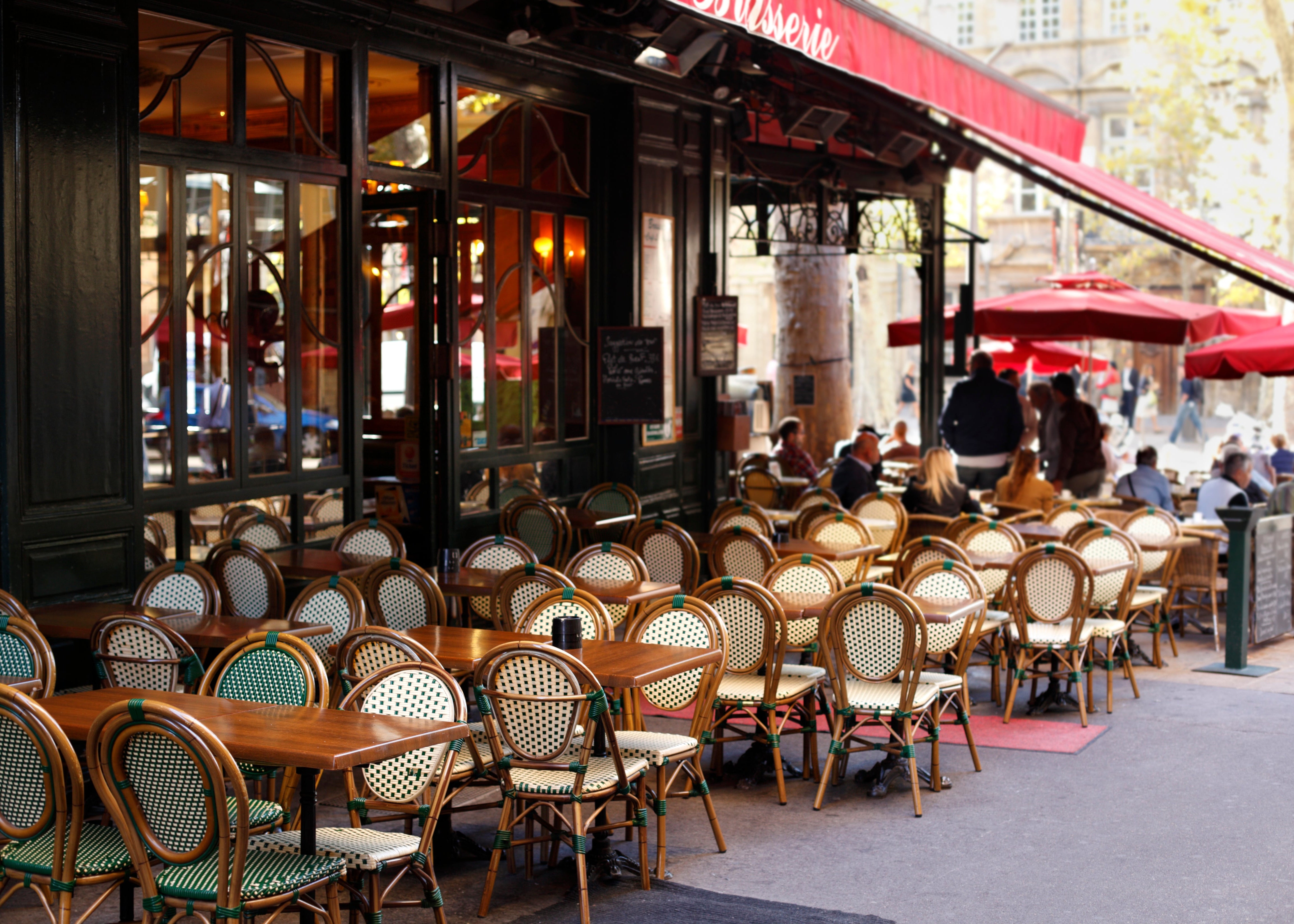 Terrasse de restaurant avec mobilier bistrot, store et façade traditionnelle parisienne. Renobat réalise l'aménagement et la rénovation de vos restaurants, cafés et brasseries à Paris et Île-de-France.