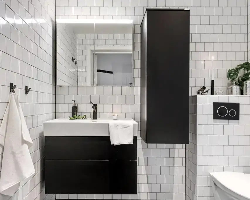 Salle de bain moderne avec carrelage mural blanc, meuble noir, miroir et accessoires épurés