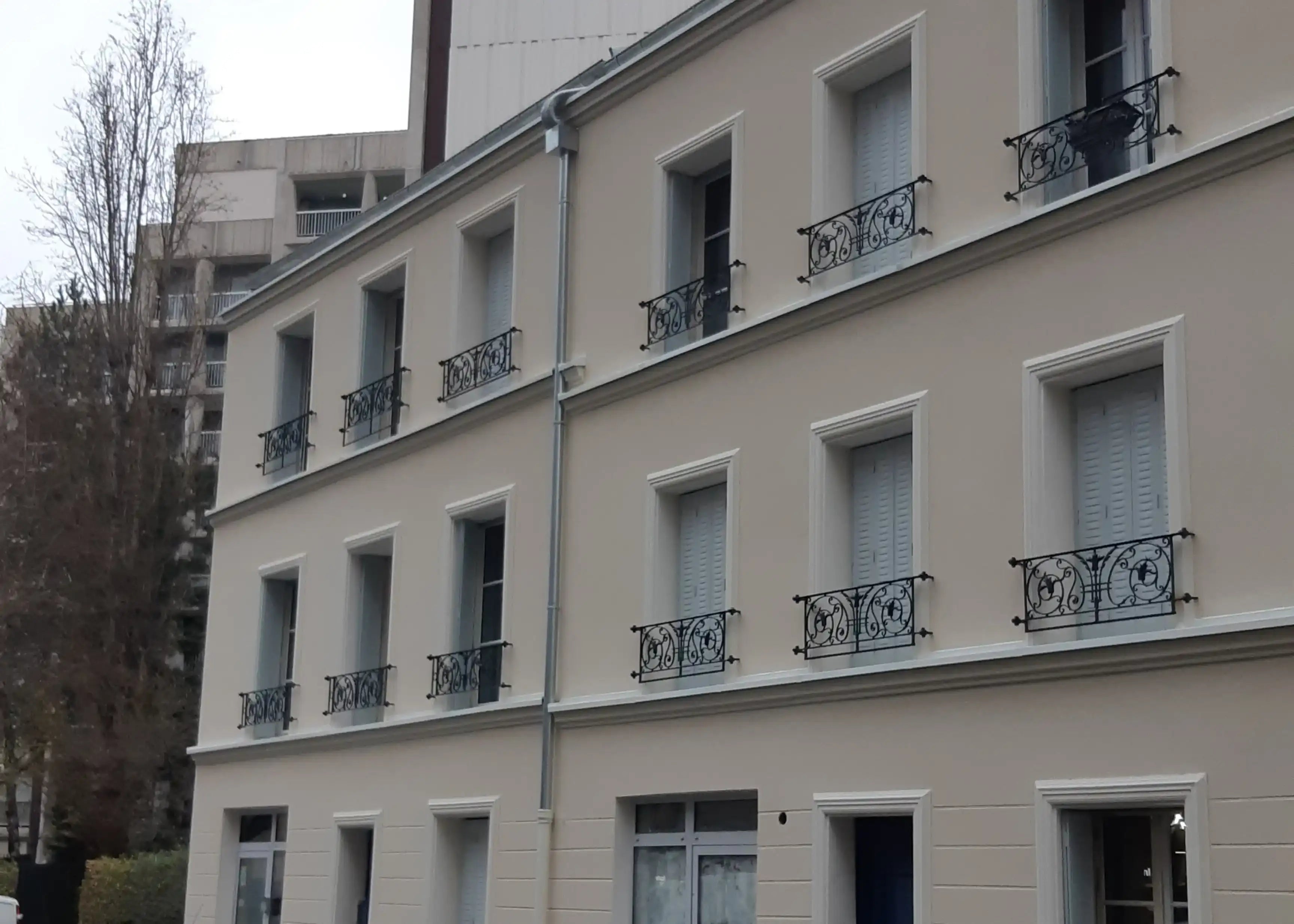 Ravalement façade plâtrée d'un immeuble ancien rénové avec balcons en fer forgé