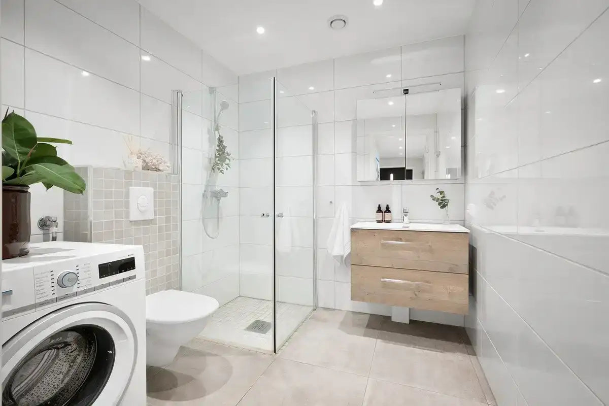 Salle de bain moderne rénovée avec douche à l'italienne, meuble en bois, lave-linge et carrelage blanc