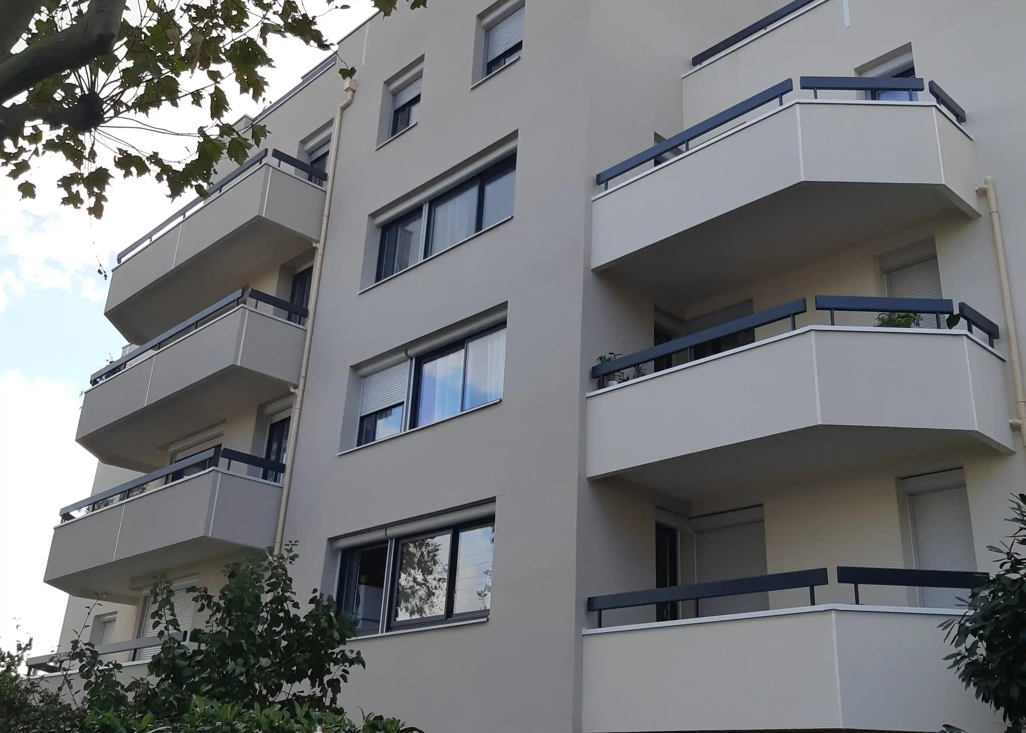 Façade rénovée d'un immeuble moderne avec balcons et fenêtres, enduit lisse beige