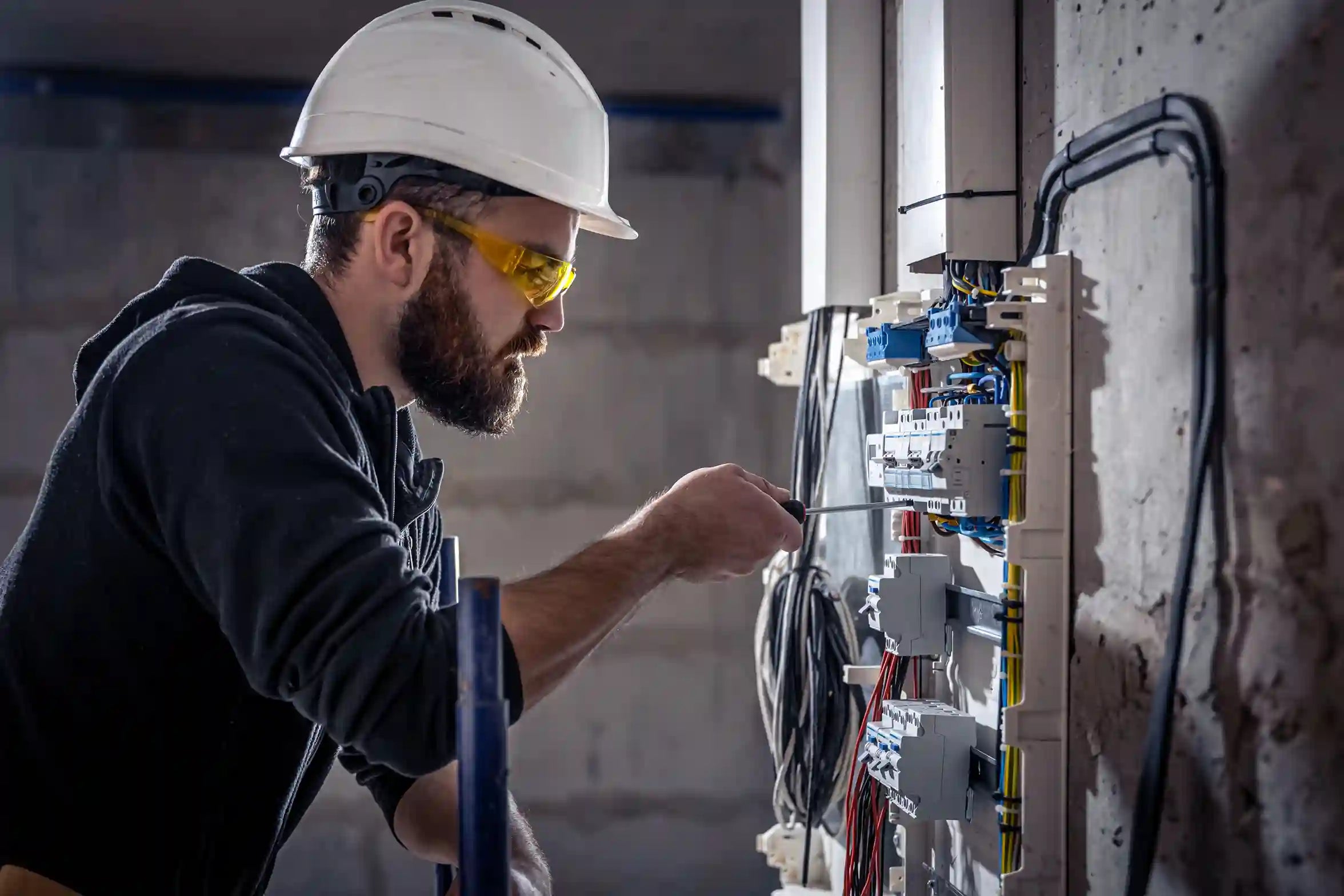 Électricien professionnel intervenant sur un tableau électrique complexe