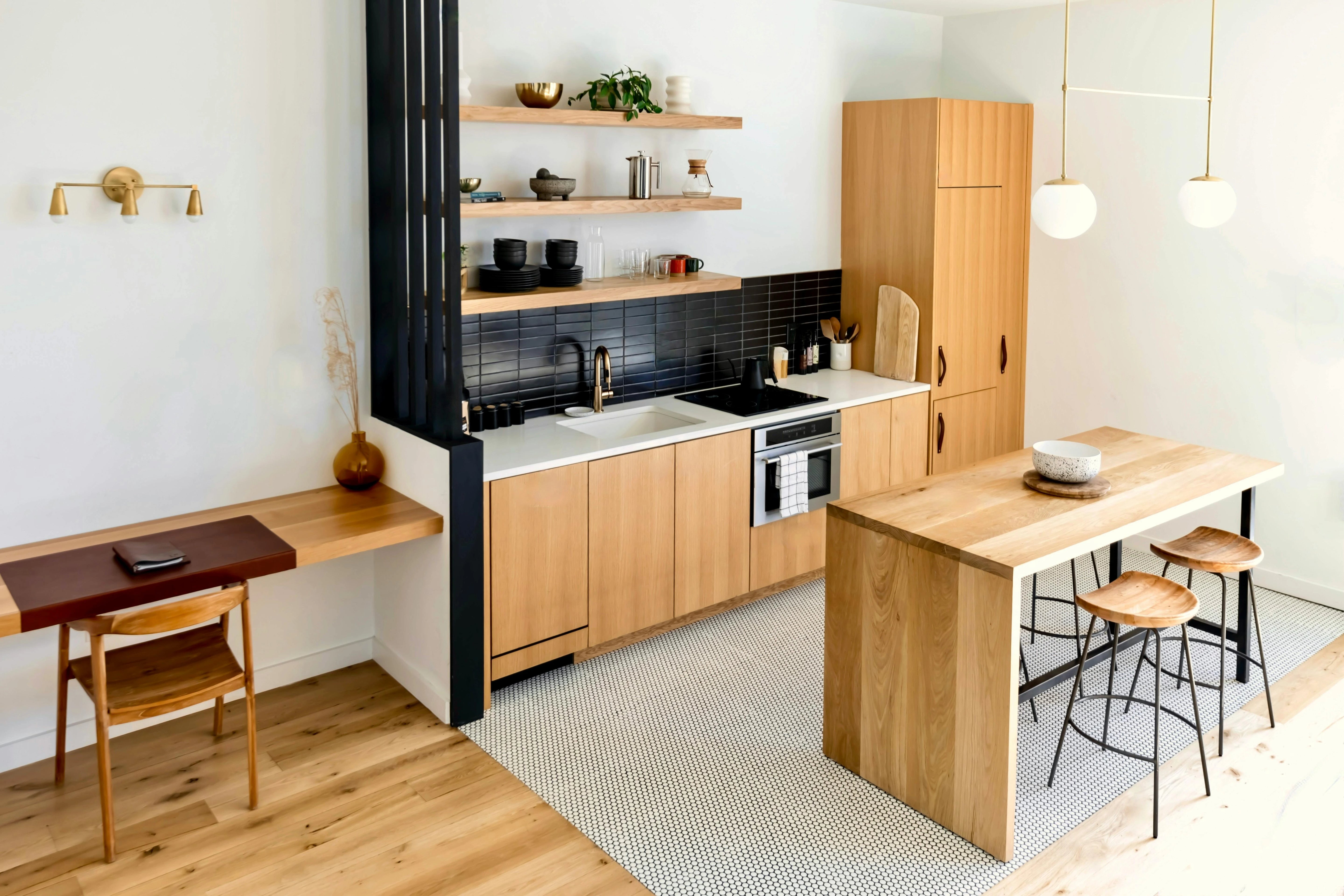 Rénovation intérieure moderne - Espace ouvert bois clair avec îlot central, crédence noire et étagères murales
